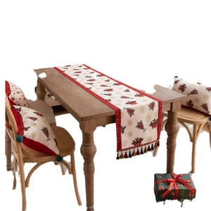 Christmas table runner with tree patterns, red plaid borders and tassels on wooden table