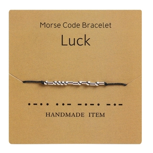 Detailansicht des Morse-Code-Armbandes mit Luck-Botschaft auf Kraftpapierkarte