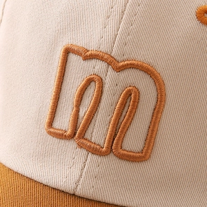 Close-up of embroidered 'm' letter on cotton twill beige and brown baseball cap
