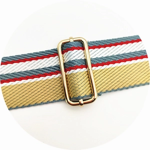Detail of adjustable colorful striped fabric bag strap with gold metal buckle
