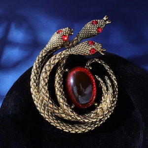 Detail of vintage gold snake brooch with red crystal gemstone and scale texture
