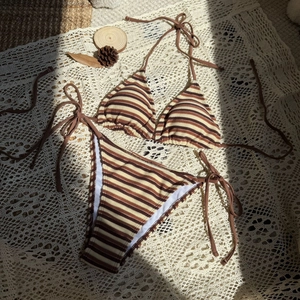 Dettaglio del set bikini a righe in spugna con laccetti laterali su pizzo all'uncinetto