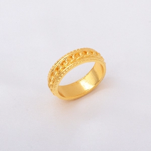 Macro shot of gold-plated ring with Cuban link chain pattern on white fabric