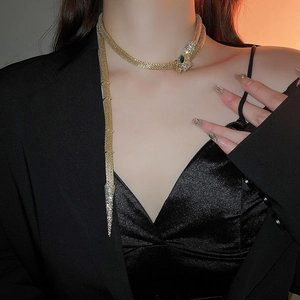 Detailed view of golden snake choker with crystal pavé and green emerald eyes