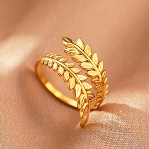 Macro view of gold olive leaf ring with detailed bypass design on champagne silk