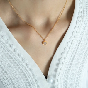 Close-up of a heart-shaped pink stone pendant on a delicate gold-plated titanium chain