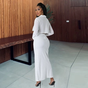 Détail de chemise courte blanche à manches longues et jupe longue rayée à taille haute