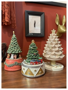Detailed view of three vintage Christmas tree music boxes with intricate festive figurines