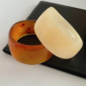 Close-up of resin bangles in amber tortoise and cream white on black leather