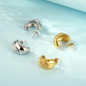 Detail of minimalist gold and silver stainless steel earrings with spiral texture