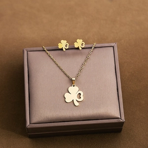 Detailed close-up of golden clover earrings and necklace set on a brown velvet display