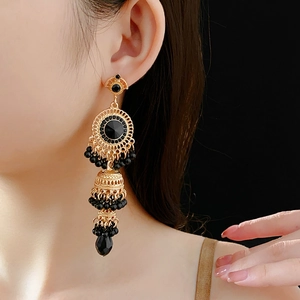 Detail of elegant gold vintage earrings with black teardrop crystals on model