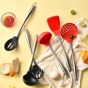 Kitchen utensil set with stainless steel handles and red silicone heads in a rustic setting