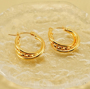 Macro detail of gold triple-layered C-shaped earrings with braided texture