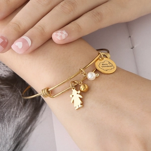 Détail d'un bracelet doré avec breloque Merry Christmas et perles porté au poignet