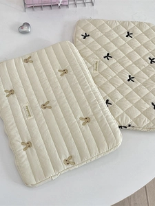 Quilted cotton laptop sleeve with cute rabbit embroidery and bow detail on a white surface