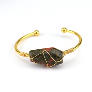 Detailed wire-wrapped unakite crystal stone on a golden open bangle bracelet