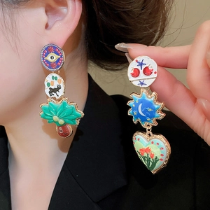Detailed shot of mismatched enamel heart earrings with celestial and floral patterns