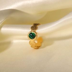 Detail of 18K gold ring featuring a green malachite stone on soft beige satin fabric