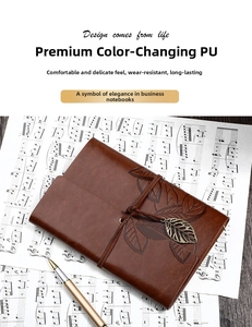 Detail of vintage brown PU leather leaf journal with metallic pendant and pen