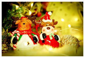 Close-up of cute clay reindeer bells ornaments on a plush white surface with warm lights