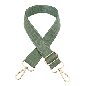 Close-up of sage green geometric maze pattern woven bag strap with gold metal hardware