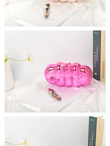 Macro shot of pink metallic wave clutch on white silk with elegant lifestyle props
