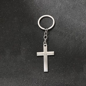 Macro detail of silver cross keychain with Spanish Lord's Prayer engraving on metal