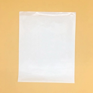 Detail of white self-adhesive shipping bag with seal strip on yellow backdrop