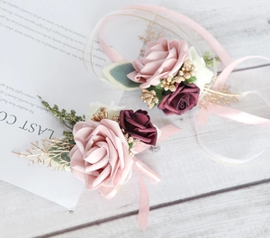 Detail of rose boutonniere and wrist corsage with silk ribbons on white wood