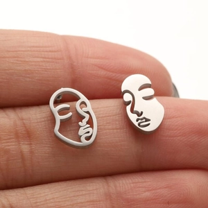 Asymmetric silver stainless steel earrings featuring abstract face art designs