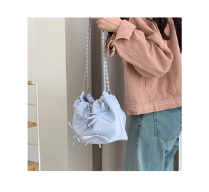 Close-up of light blue bucket bag featuring soft pleats and sweet ribbon bow details