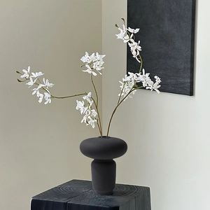 Vaso artistico in ceramica nera opaca con fiori finti bianchi in stile estetico wabi-sabi