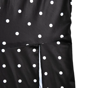 Detail view of black dress featuring white polka dot patterns and side slit design