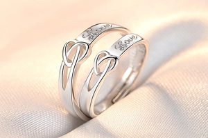 Close-up of silver couple rings featuring heart hollow design and love engraving