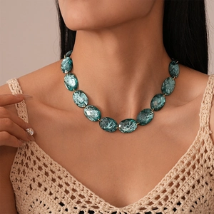 Detailed view of teal oval resin beads with marble texture on a gold chain necklace