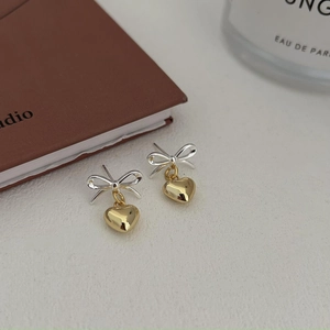 Detailed close-up of bow and golden heart drop earrings on a vintage book