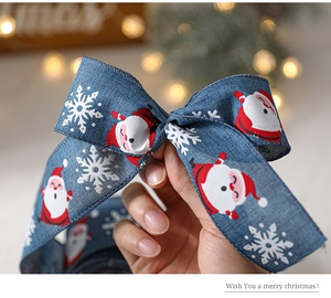Gros plan d'un nœud de Noël avec motifs Père Noël et flocons sur ruban bleu texturé