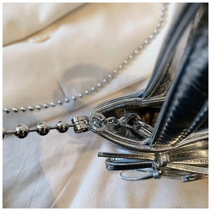 Close-up of silver metallic textured handbag featuring a matching beaded chain strap
