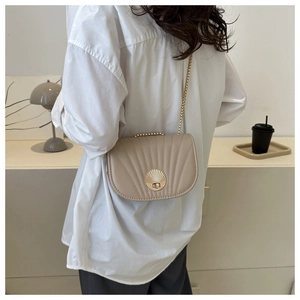 Detail of beige saddle bag with shell-textured leather and golden metal clasp