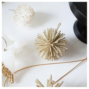 Close-up of glittery white and gold Christmas ornaments including pinecones and birds