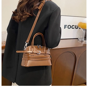 Model wearing a vintage brown leather crossbody bag with adjustable strap and shell design