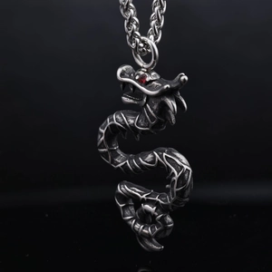 Macro shot of vintage silver dragon pendant with detailed scales and a red gem eye