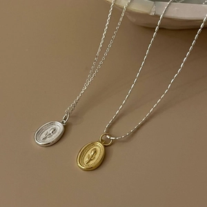 Close-up of gold and silver oval flower relief necklaces with detailed chain textures