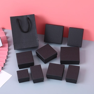 Detail of black litchi texture jewelry boxes with matching gift bags on two-tone background