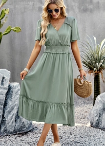 Detail of green V-neck dress featuring ruffled hem and elastic waist in an outdoor setting