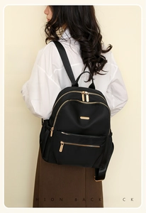 Fashionable black nylon waterproof backpack with gold zippers shown on a female model