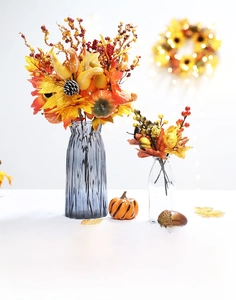 Detail of Halloween floral arrangement with pumpkins, berries, maple leaves, and glass vases