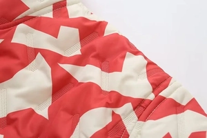 Détail du tissu matelassé rouge et crème avec gaufrage géométrique et mesh respirant