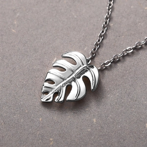 Detailed macro shot of a silver Monstera leaf pendant with a high-polished mirror finish